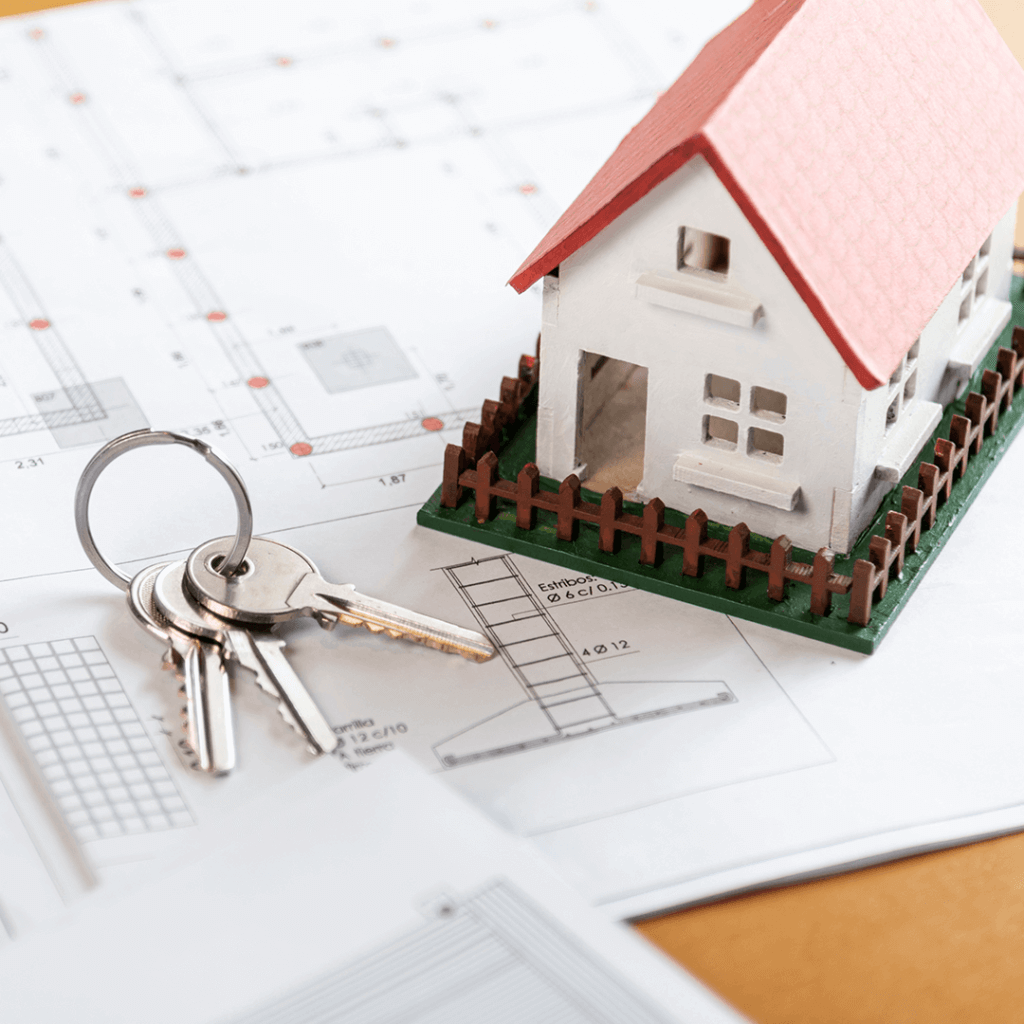 Miniaturka domu oraz klucze widoczne na tle planów budowy domu